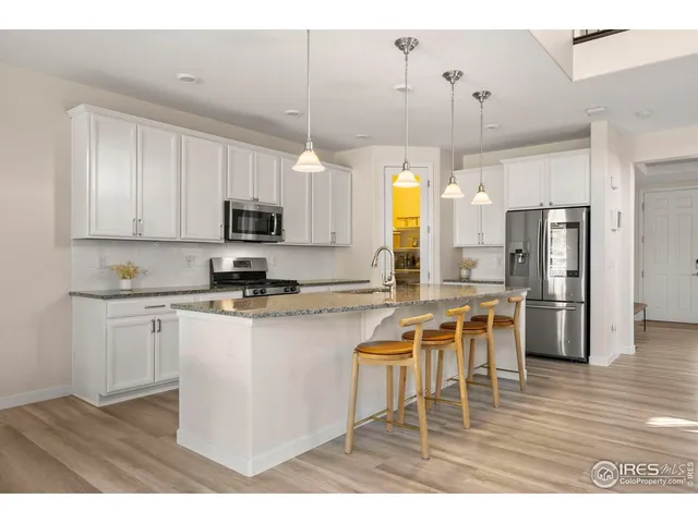 a kitchen with stainless steel appliances a stove a sink a refrigerator a center island and a window