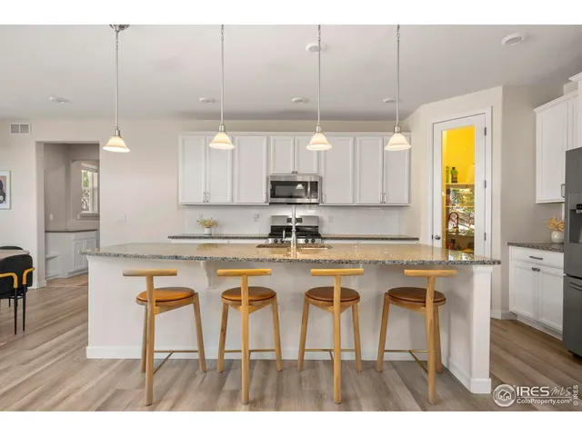 a kitchen with kitchen island granite countertop a table chairs a sink dishwasher window and cabinets