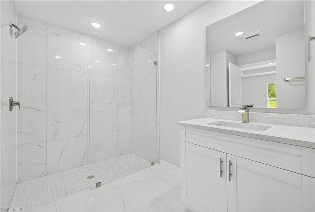 321 Ranier Avenue Lehigh Acres, FL 33974 - Photo 17 of 40 a bathroom with a shower sink vanity and mirror