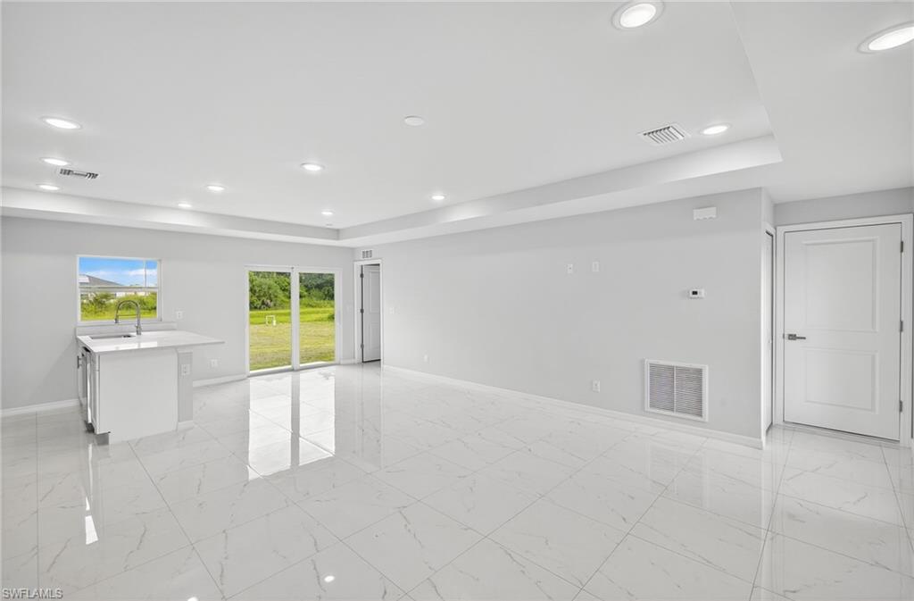 321 Ranier Avenue Lehigh Acres, FL 33974 - Photo 4 of 40 a view of an empty room with a window and kitchen view