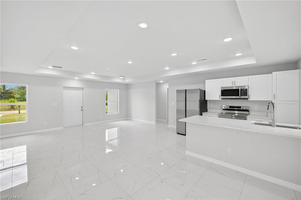 321 Ranier Avenue Lehigh Acres, FL 33974 - Photo 9 of 40 a large white kitchen with stainless steel appliances