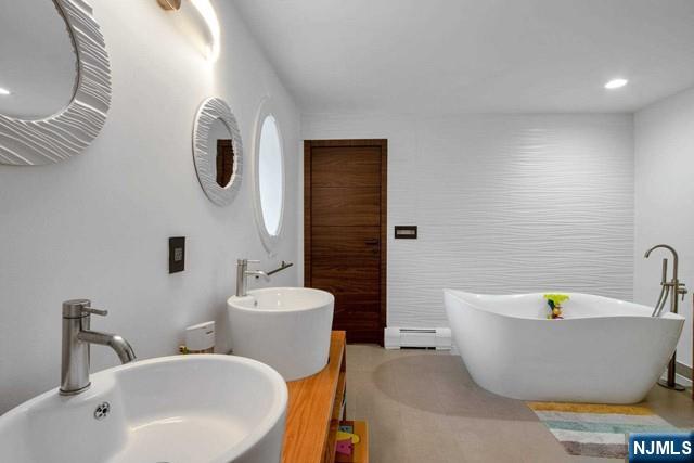 99 Ogle Road Old Tappan, NJ 07675 - Photo 36 of 50 a bathroom with a white tub a sink and a mirror