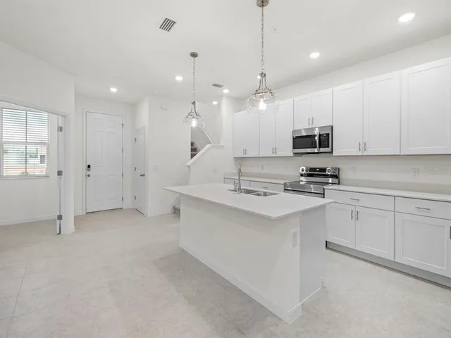 a kitchen with kitchen island granite countertop a sink a center island stainless steel appliances and cabinets