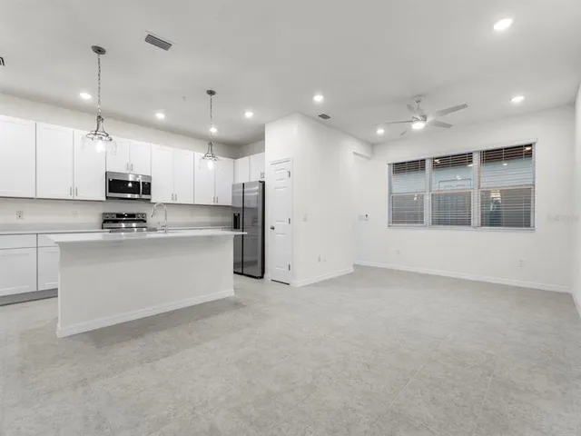 a view of a kitchen with stainless steel appliances kitchen island white cabinets and a refrigerator