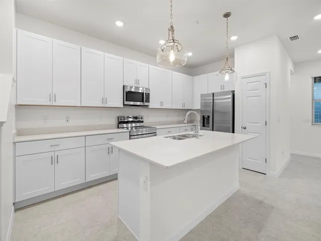 a kitchen with kitchen island white cabinets and stainless steel appliances