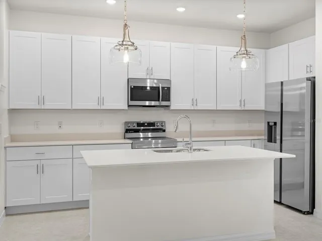 a kitchen with stainless steel appliances granite countertop a sink refrigerator and microwave