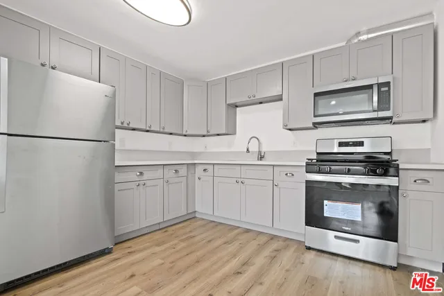 a kitchen with cabinets stainless steel appliances and wooden floor