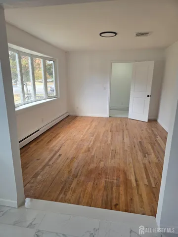 a view of an empty room with wooden floor and a window