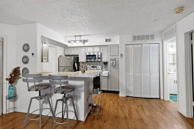 a kitchen with stainless steel appliances a refrigerator a stove a sink dishwasher and white cabinets with wooden floor