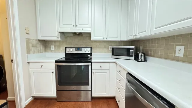 a kitchen with white cabinets and stainless steel appliances