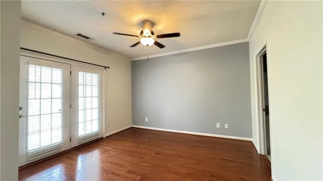 an empty room with wooden floor fan and windows
