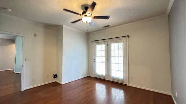 an empty room with wooden floor fan and windows