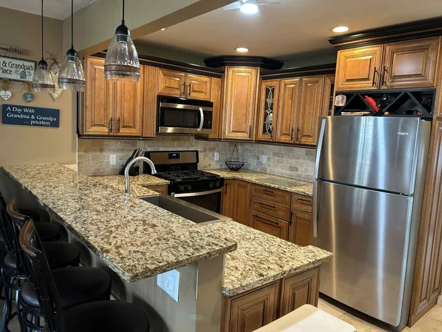 a kitchen with stainless steel appliances granite countertop a refrigerator a stove top oven a sink and dishwasher