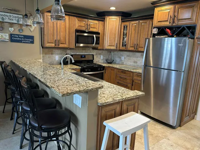 a kitchen with stainless steel appliances granite countertop a stove a refrigerator a microwave a sink and chairs