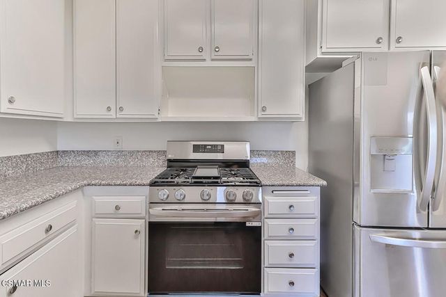 a kitchen with granite countertop white cabinets and stainless steel appliances