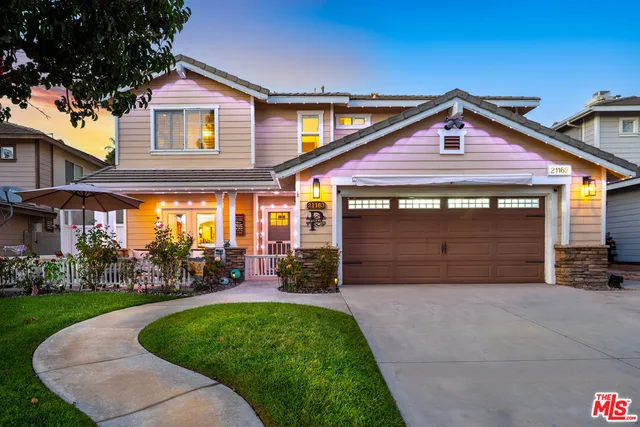 a view of a house with a yard potted plants and a table