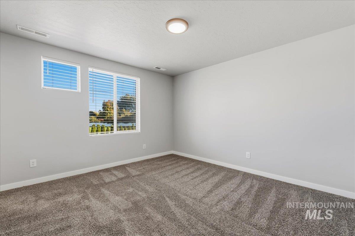 12509 West Victory Road Boise, ID 83709 - Photo 13 of 23 Neutral wall paint, plush carpet, contemporary ceiling light fixture, and window blinds