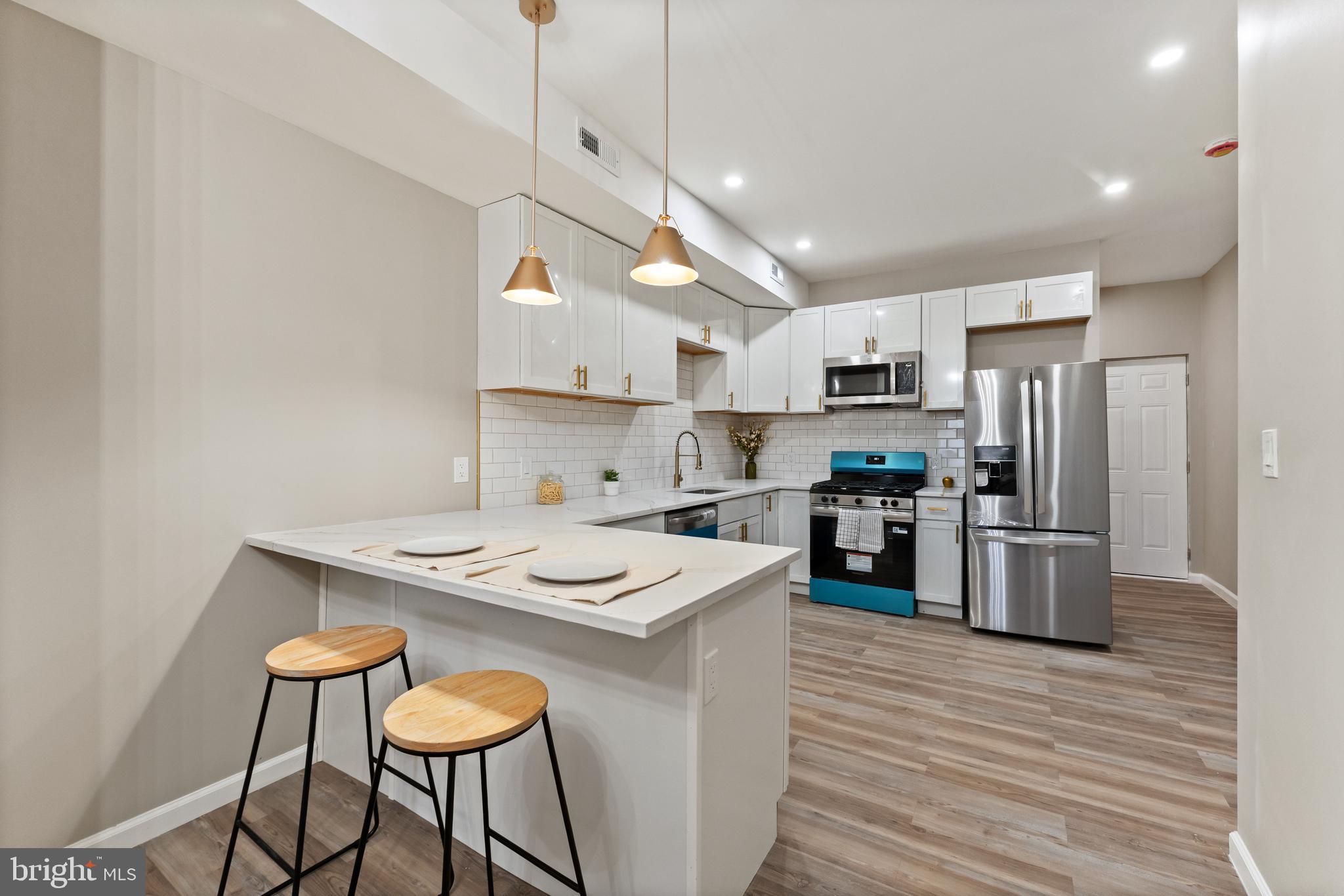 602 Denison Street Baltimore, MD 21229 - Photo 2 of 17 a kitchen with kitchen island a stove a table and chairs