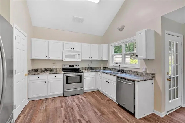 a kitchen with stainless steel appliances granite countertop a stove and white cabinets