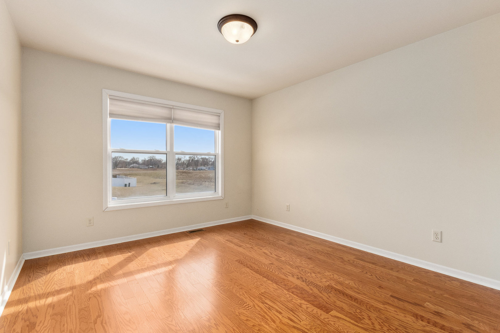 415 Davidson Drive Minooka, IL 60447 - Photo 8 of 18 an empty room with wooden floor and windows
