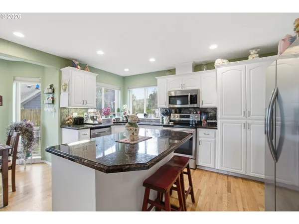 a kitchen with stainless steel appliances granite countertop a refrigerator a stove and a sink