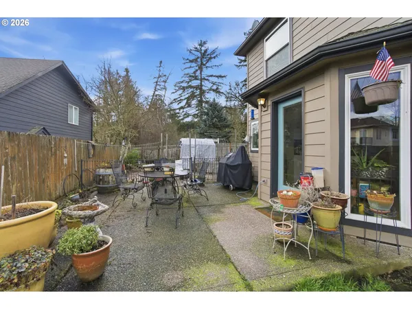 a view of a patio with table and chairs potted plants and a large tree