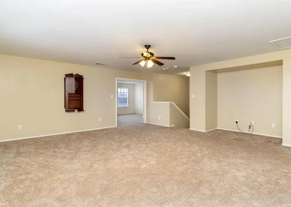 an empty room with windows and a ceiling fan