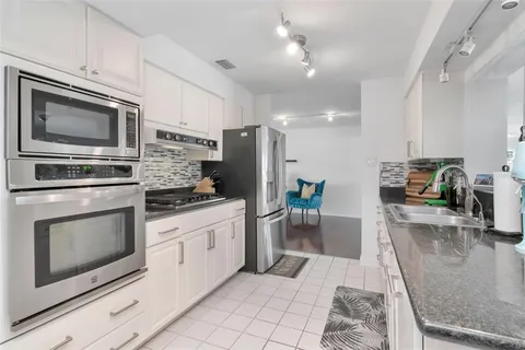 a large white kitchen with a sink and cabinets