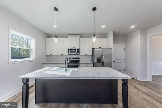 a kitchen with kitchen island a stove a refrigerator a sink dishwasher with a dining table and chairs