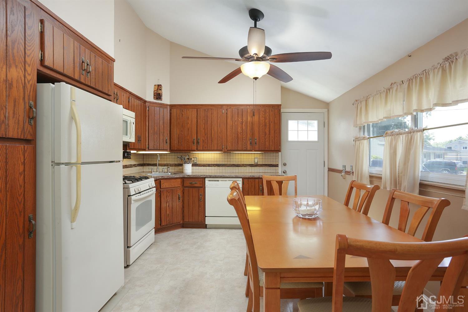 103 Westminster Road Colonia, NJ 07067 - Photo 8 of 26 a kitchen with granite countertop a refrigerator a stove a sink dishwasher a dining table and chairs with wooden floor