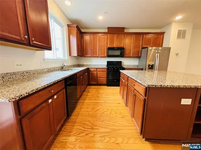a large kitchen with stainless steel appliances granite countertop wooden cabinets a sink and a granite counter tops