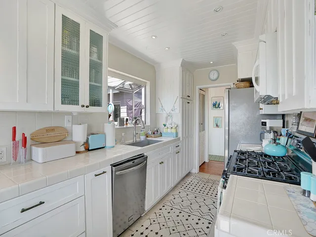 a kitchen with stainless steel appliances a sink a stove a refrigerator and cabinets