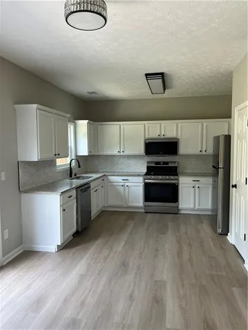 a kitchen with granite countertop a stove top oven and cabinets