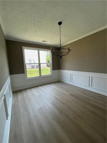 an empty room with wooden floor windows and entrance