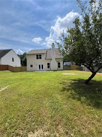 a view of a house with a big yard and large trees