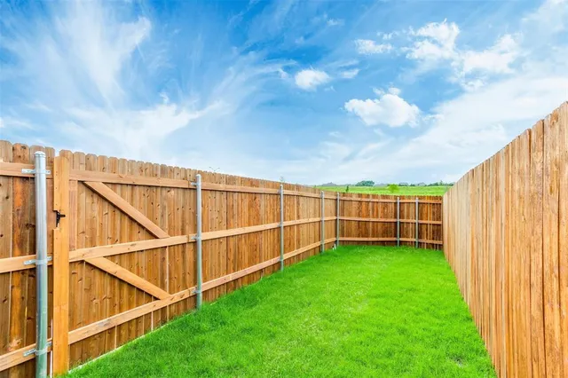 a view of a yard with wooden fence