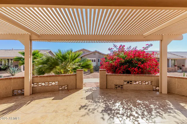 a view of a patio with table and chairs potted plants and floor to ceiling window
