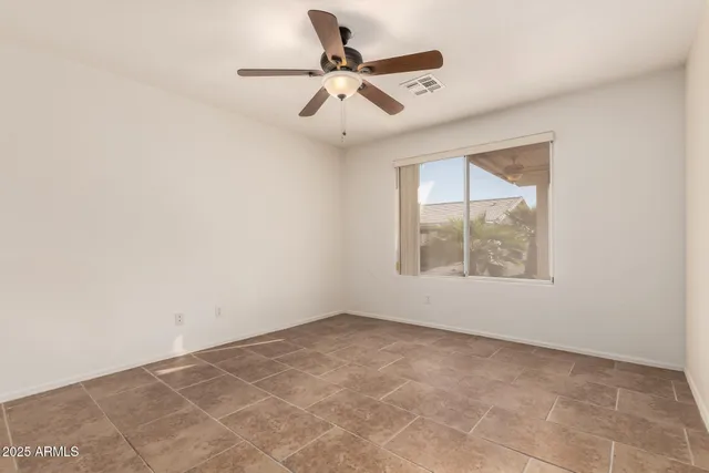 an empty room with ceiling fan and windows