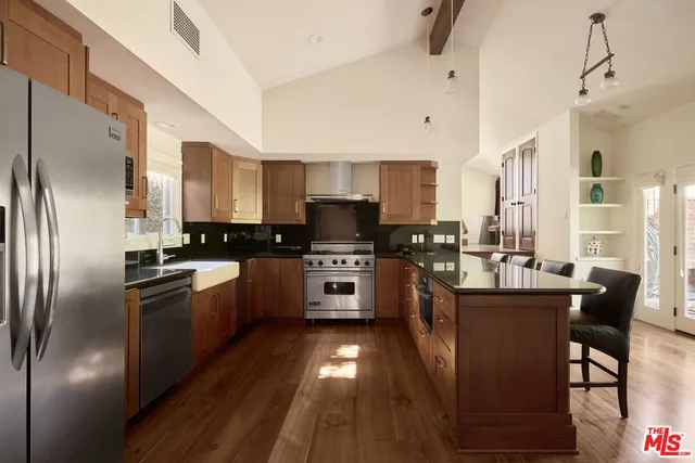 a kitchen with stainless steel appliances granite countertop a refrigerator a stove a sink dishwasher and a refrigerator with wooden floor