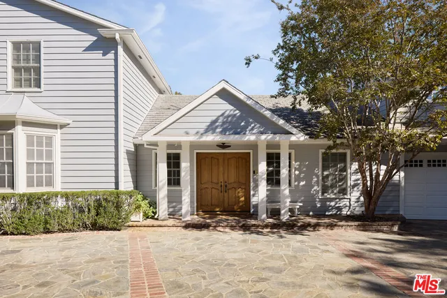 a front view of a house with a yard and potted plants