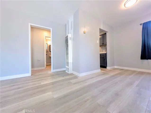 a view of an empty room with window and wooden floor