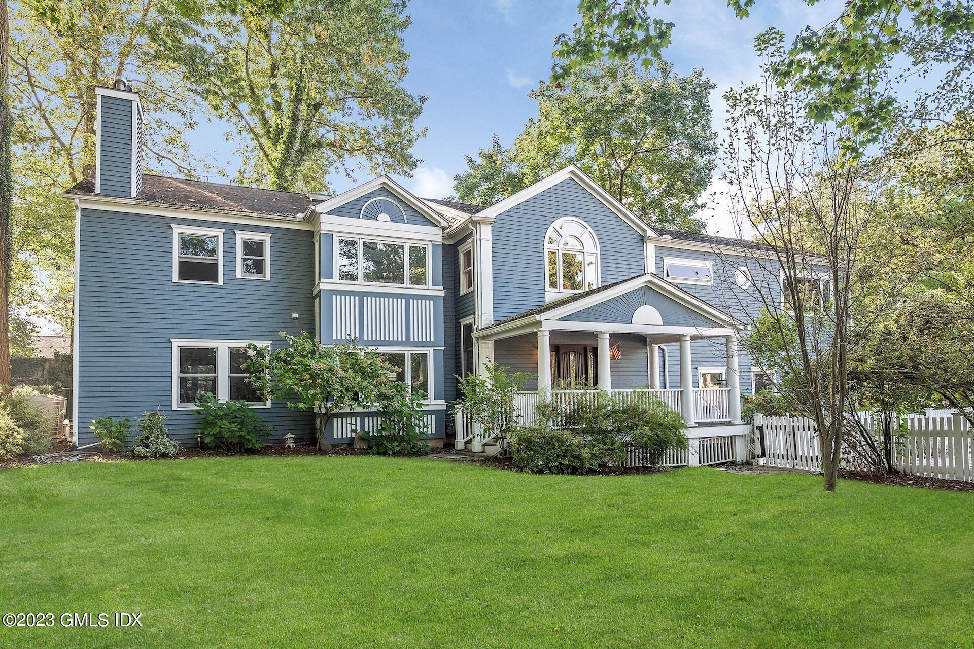 a front view of a house with a garden and trees