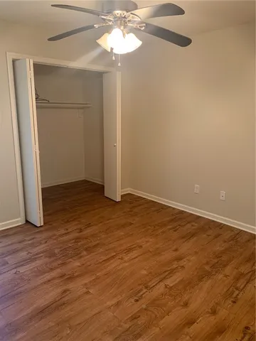 an empty room with wooden floor chandelier fan and windows