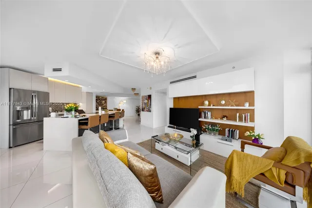 a living room with furniture a flat screen tv and kitchen view