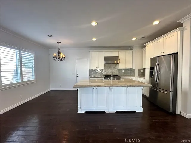 a kitchen with stainless steel appliances granite countertop a refrigerator a sink dishwasher a stove and a microwave oven on granite countertops
