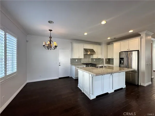 a kitchen with stainless steel appliances a sink a stove a refrigerator cabinets and a center island