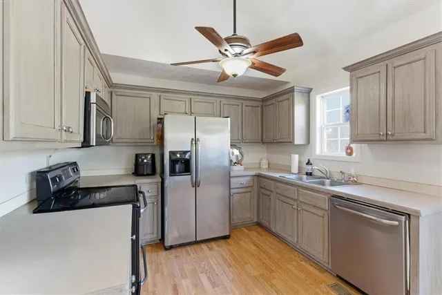 a kitchen with stainless steel appliances a sink cabinets and wooden floor