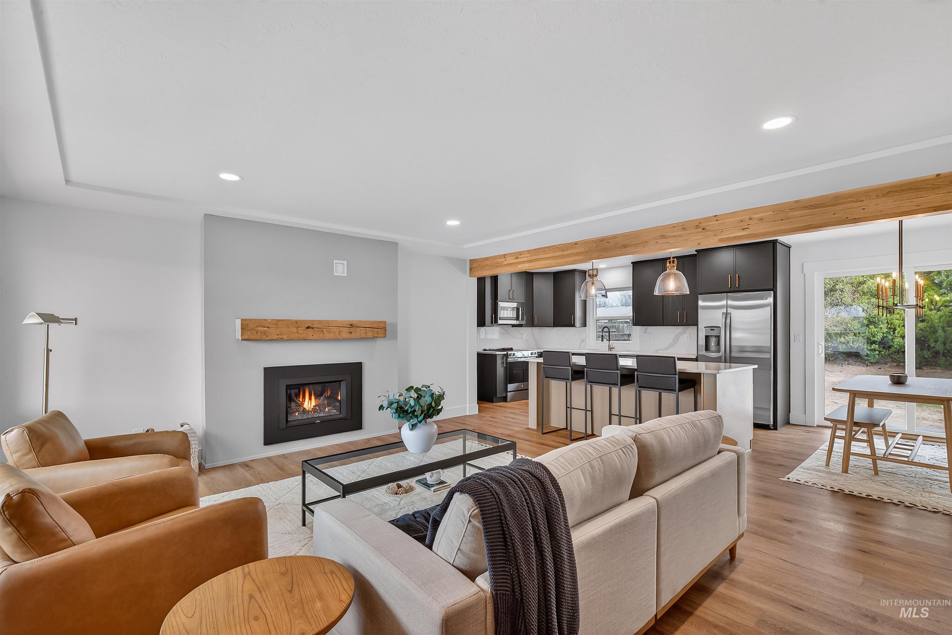 Living room with light wood-type flooring, a glass covered fireplace, recessed lighting, and plenty of natural light