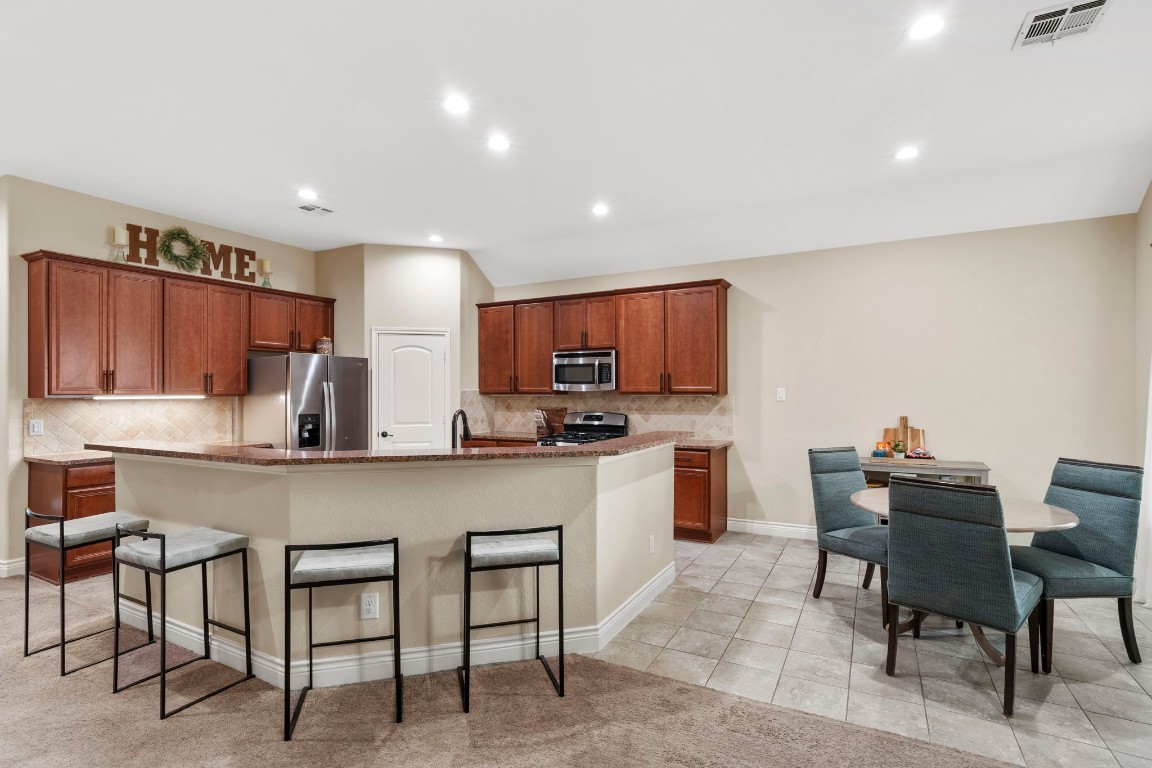 4926 Magnolia Bend Drive Rosharon, TX 77583 - Photo 8 of 27 a kitchen with stainless steel appliances granite countertop a table chairs sink and cabinets