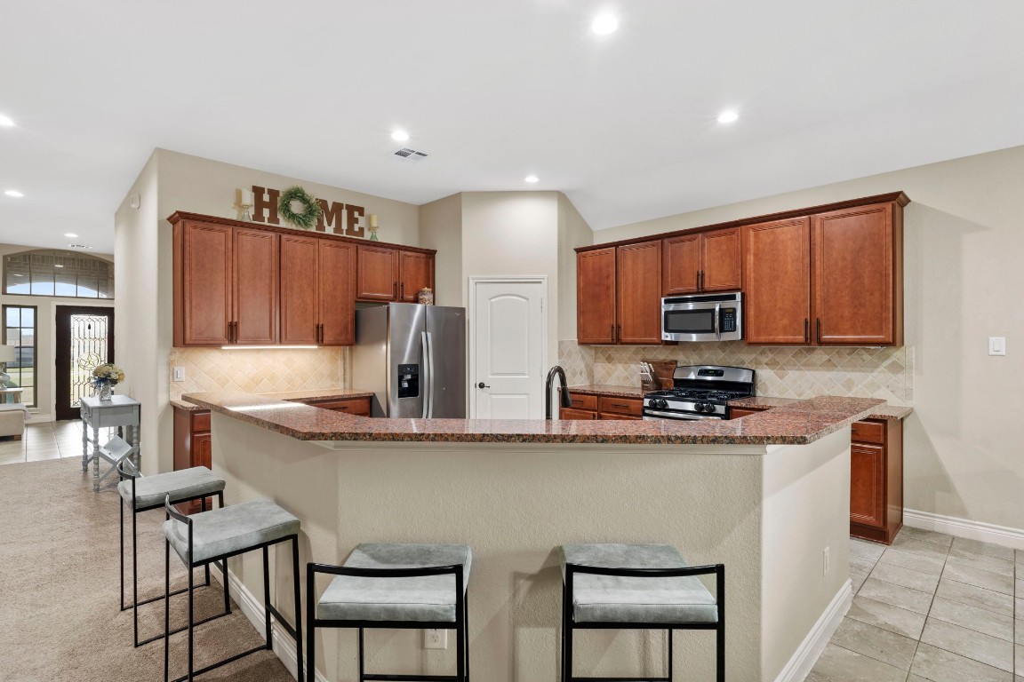 4926 Magnolia Bend Drive Rosharon, TX 77583 - Photo 9 of 27 a kitchen with stainless steel appliances a sink a stove a refrigerator cabinets and chairs
